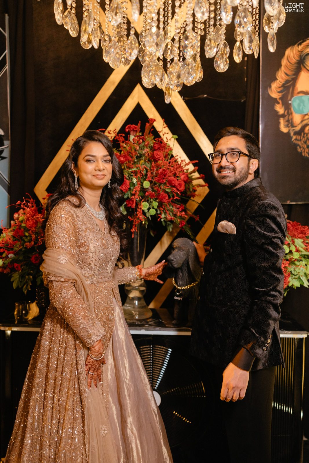 A built décor installation — floral archways, a candlelit lounge and hanging crystal