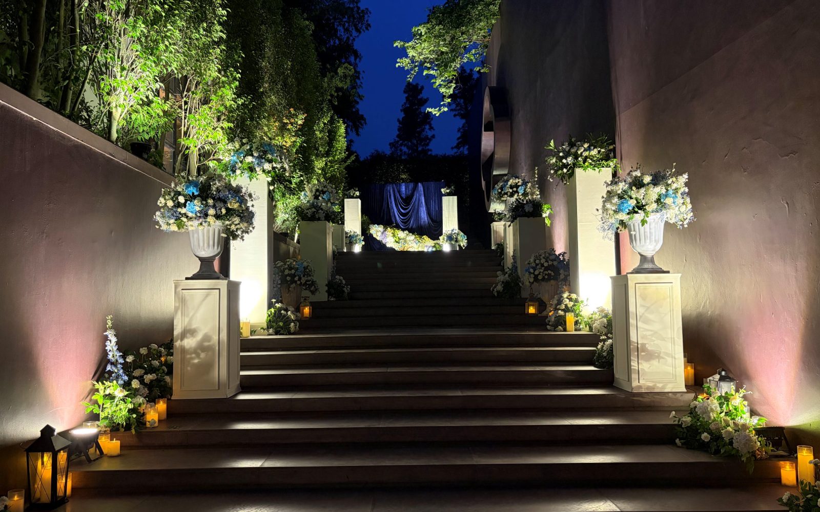 Lit staircase entrance dressed with urn florals and candle lanterns