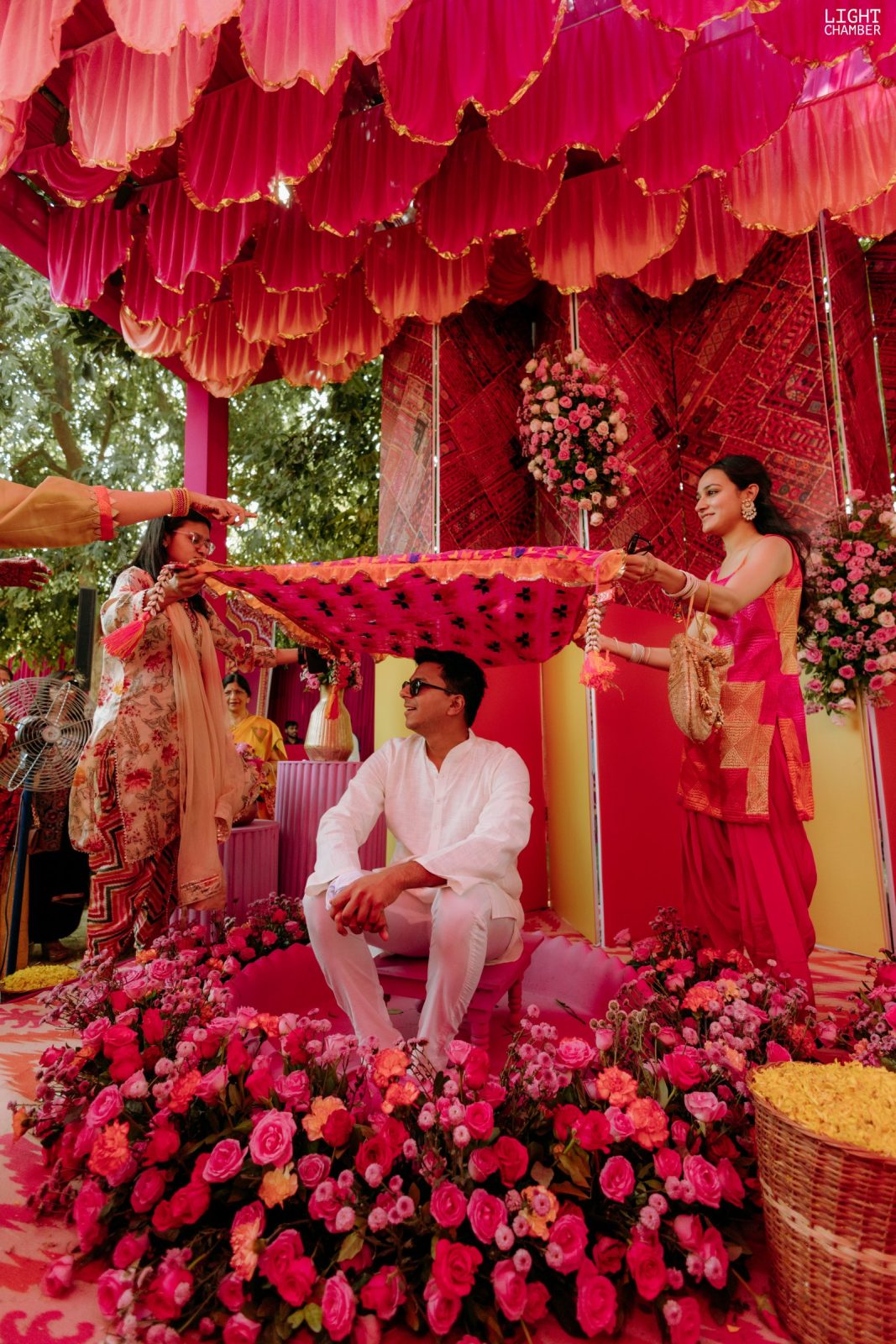 Haldi under a canopy of pink and marigold, turmeric and petals in the air