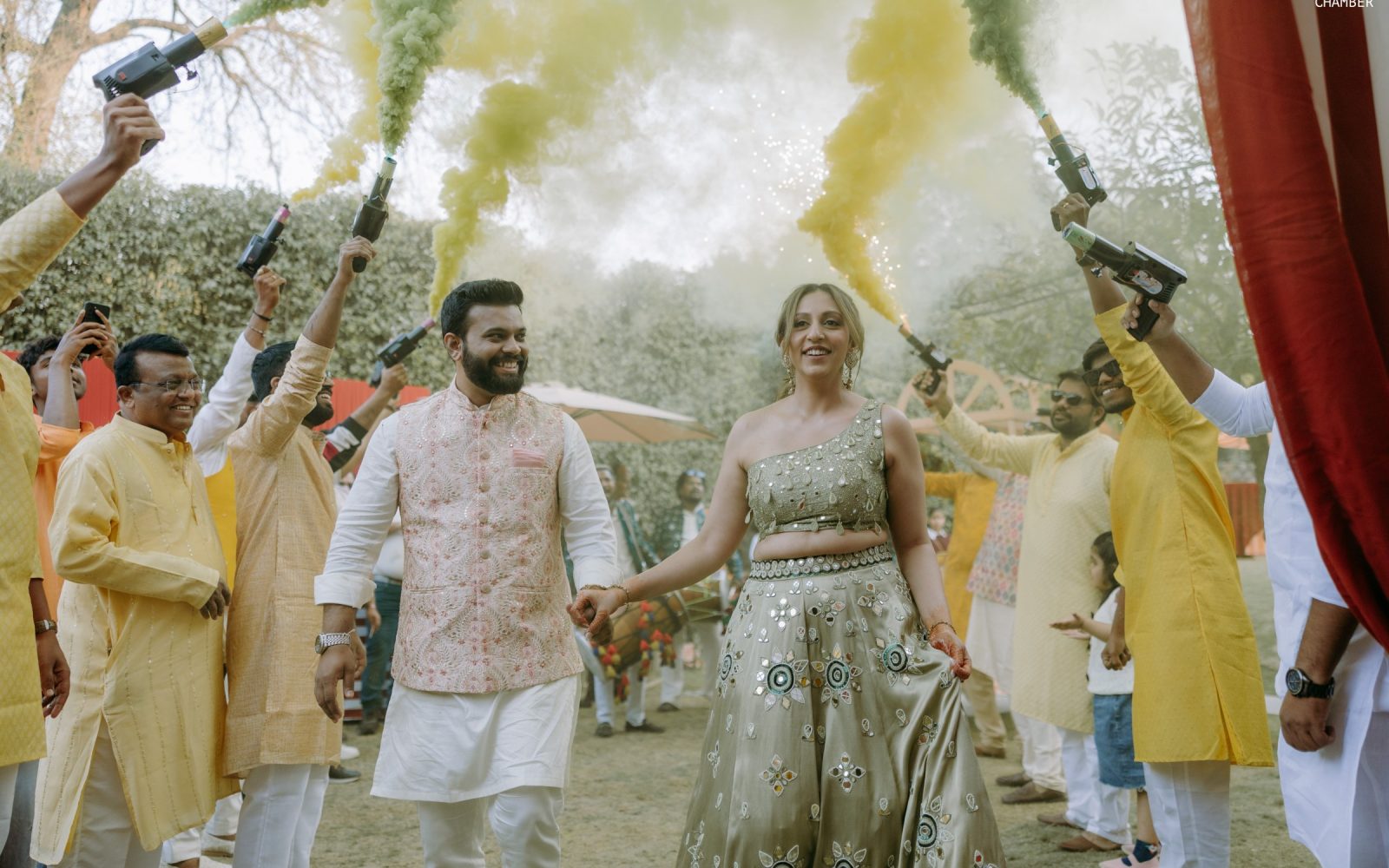 Haldi under a canopy of pink and marigold, turmeric and petals in the air