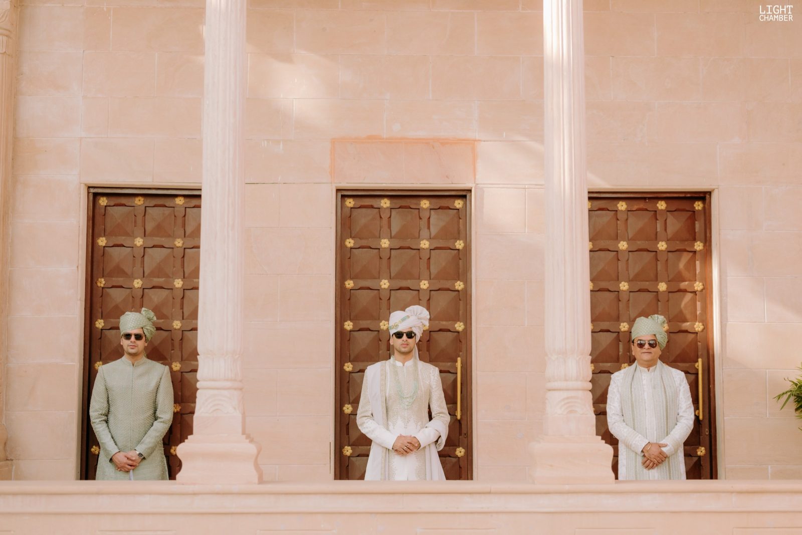 A Rajasthan palace dressed for a wedding — sandstone courtyards, lit façades and a mandap set against the hills