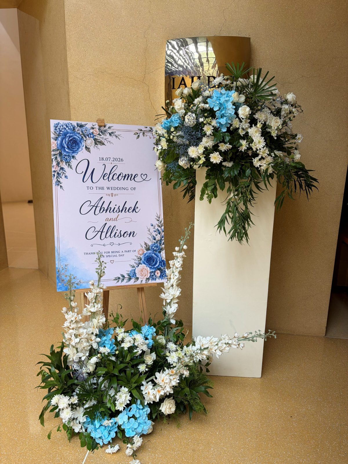 Welcome board on an easel, framed by a white and blue floral arrangement